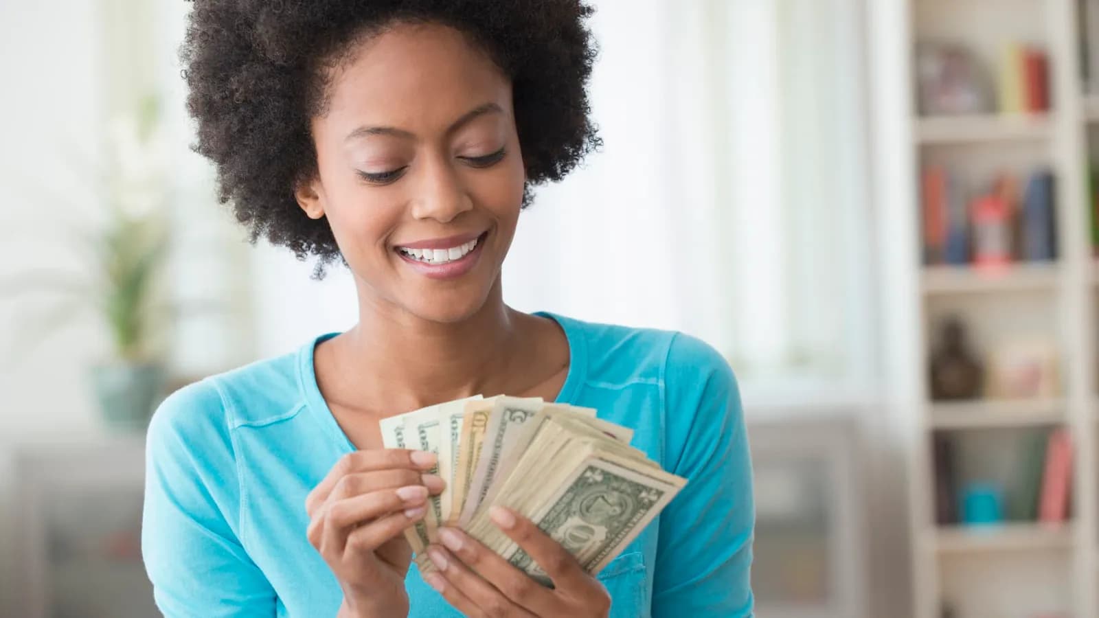 woman holding money - Cheapest Way To Travel The World