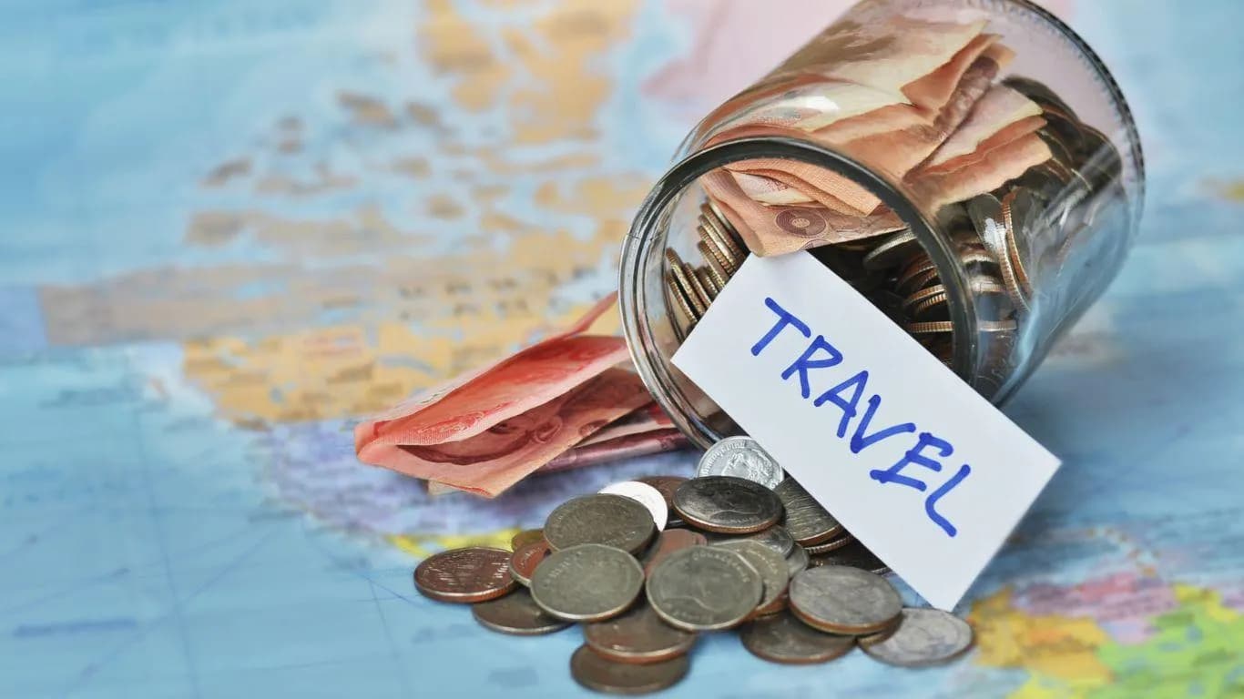 a jar of coins on a map - Best Way To Save For Travel