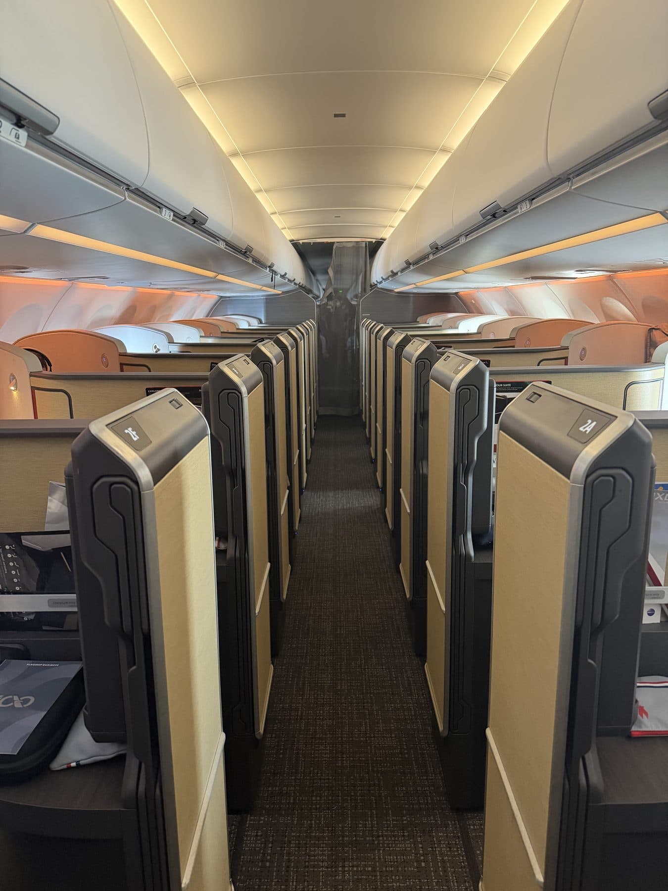 Business-class suites with sliding doors aboard a widebody jet, cabin lit in warm evening tones